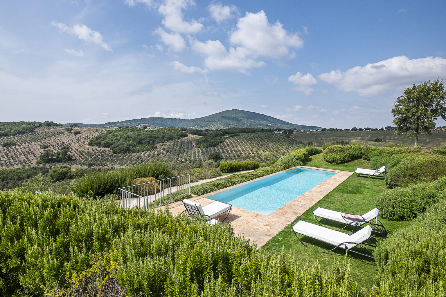 Scenic view of a luxurious villa with a swimming pool surrounded by lush greenery and rolling hills, ideal for a tranquil getaway in the countryside. | Only on SopranoVillas