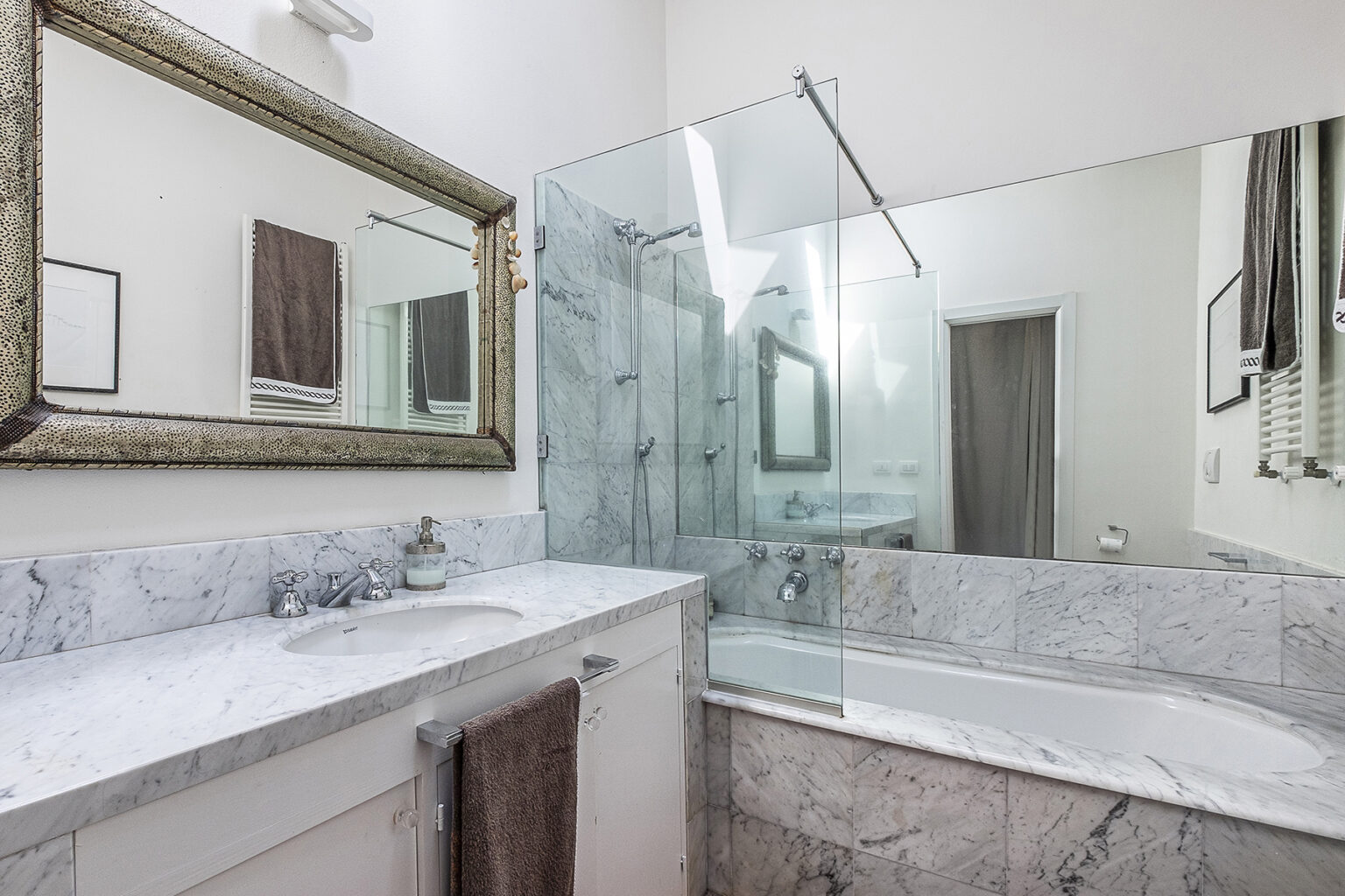 Modern bathroom featuring a marble countertop, glass shower enclosure, and a decorative mirror, showcasing a clean and elegant design. | Only on SopranoVillas