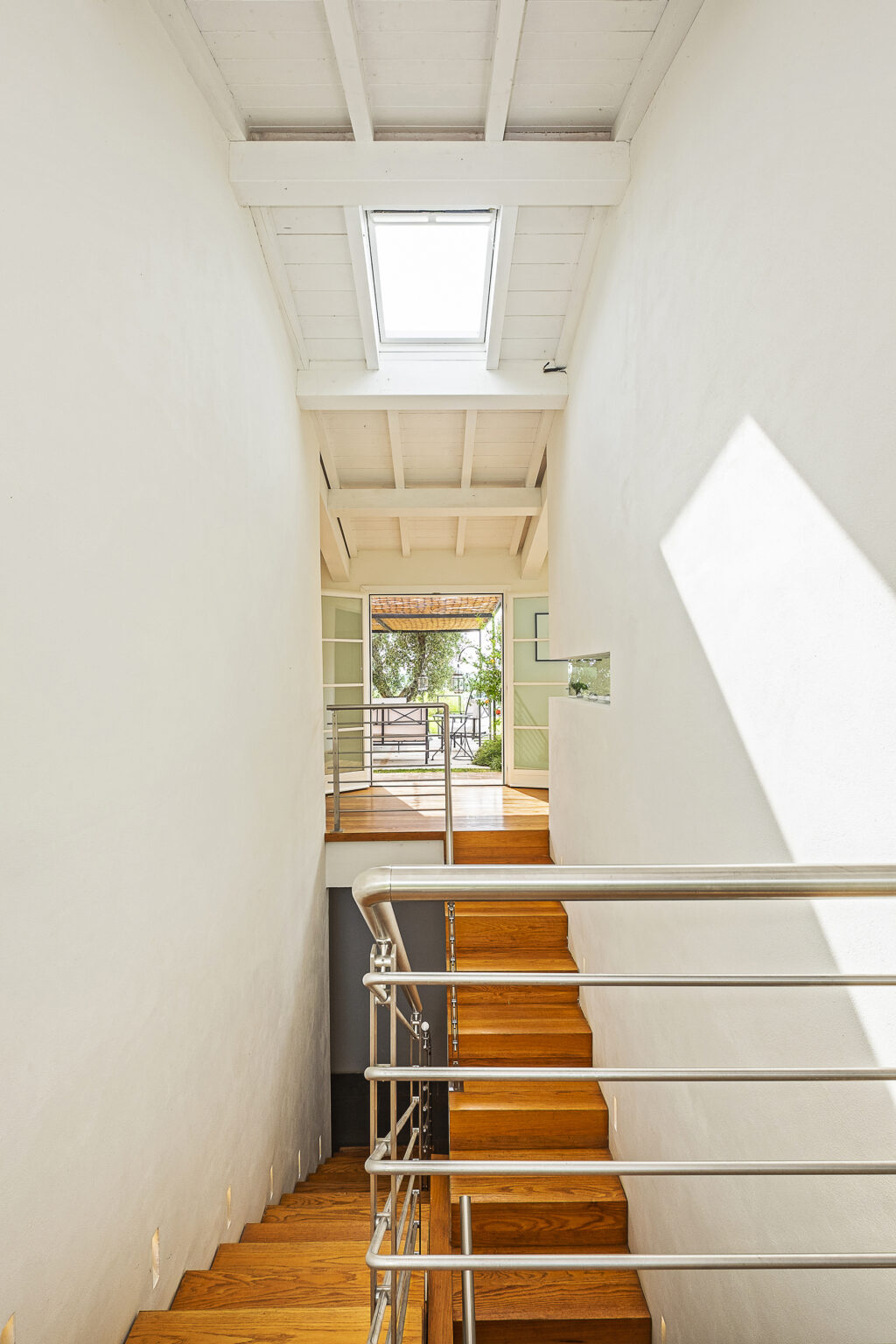 Bright and airy staircase leading to an outdoor view, featuring wooden flooring and modern railings, with natural light streaming through large windows and an open layout design. | Only on SopranoVillas