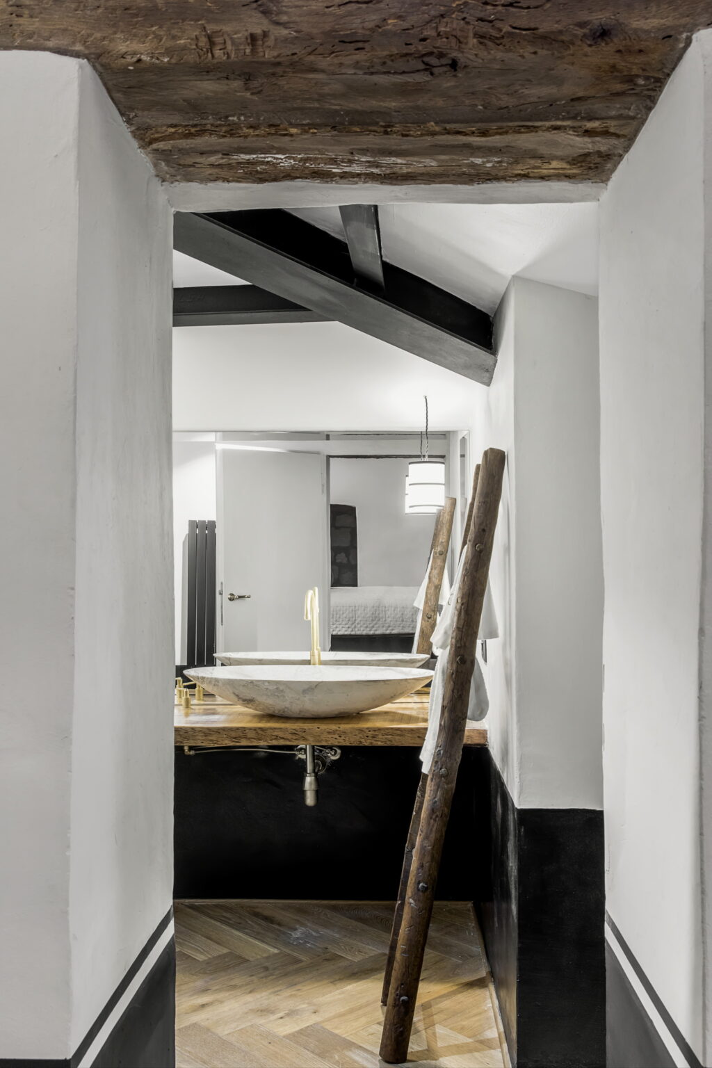 Modern bathroom design featuring a unique stone basin on a wooden countertop, framed by a minimalist white wall and rustic wooden beams, creating a stylish and serene atmosphere. | Only on SopranoVillas
