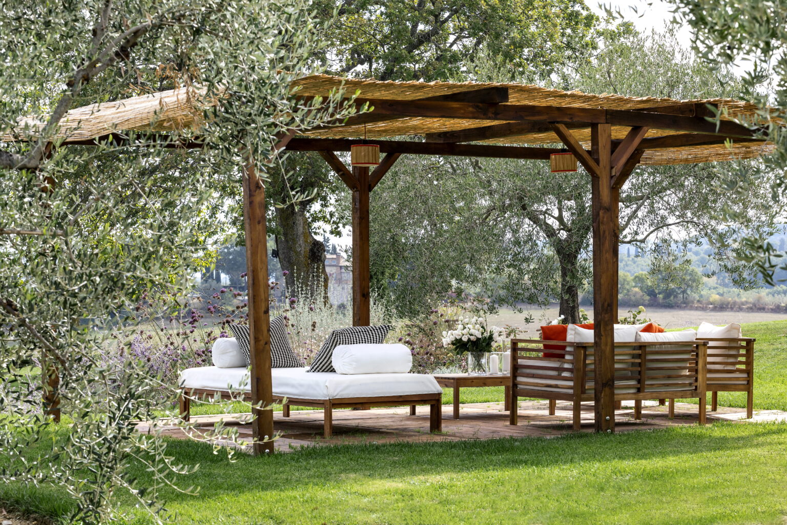 Wooden pergola with comfortable seating area surrounded by greenery, ideal for outdoor relaxation and entertaining. | Only on SopranoVillas
