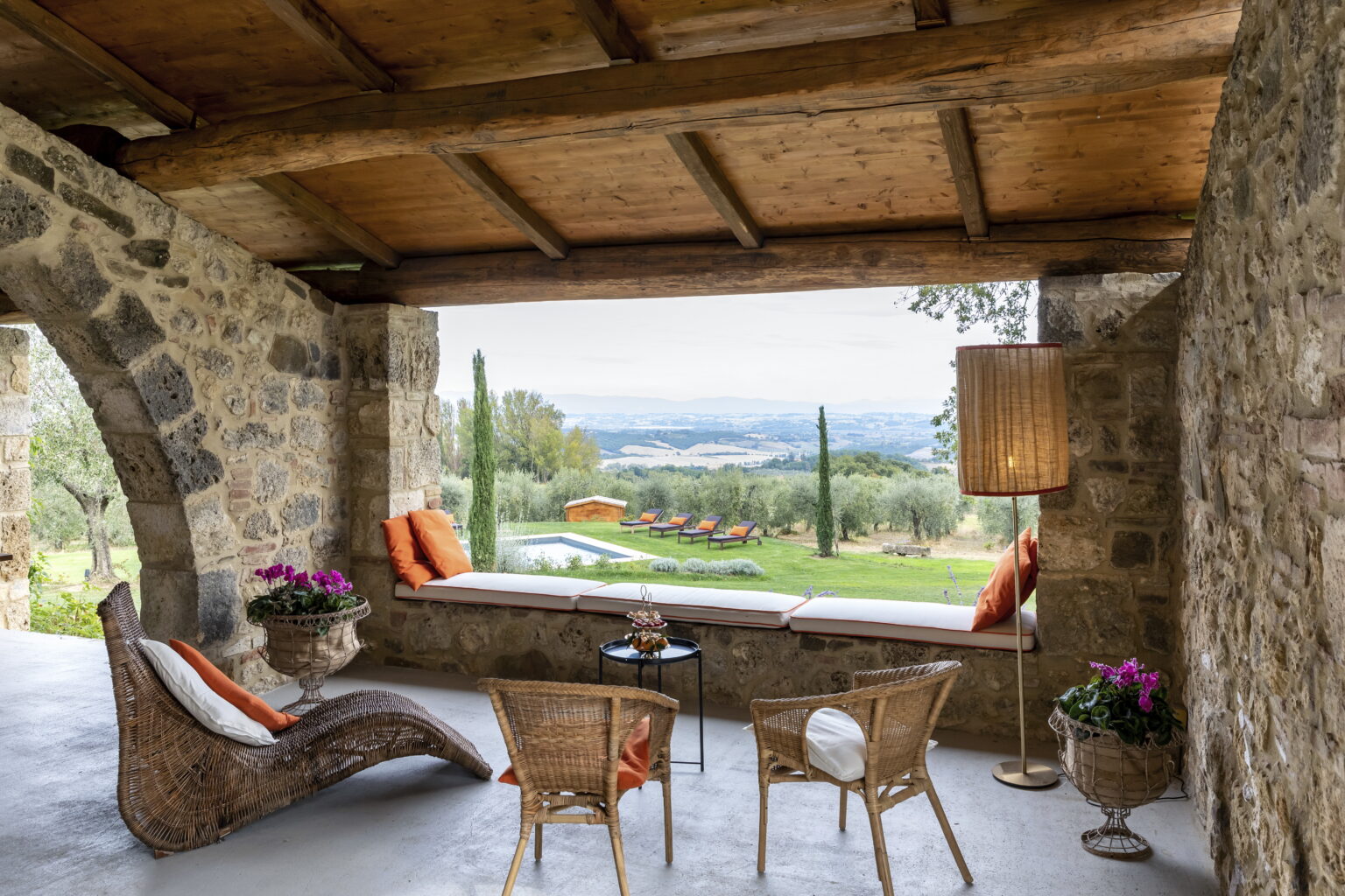 Cozy interior of a rustic stone villa with a panoramic view of a lush landscape, featuring comfortable seating, decorative plants, and warm lighting. | Only on SopranoVillas