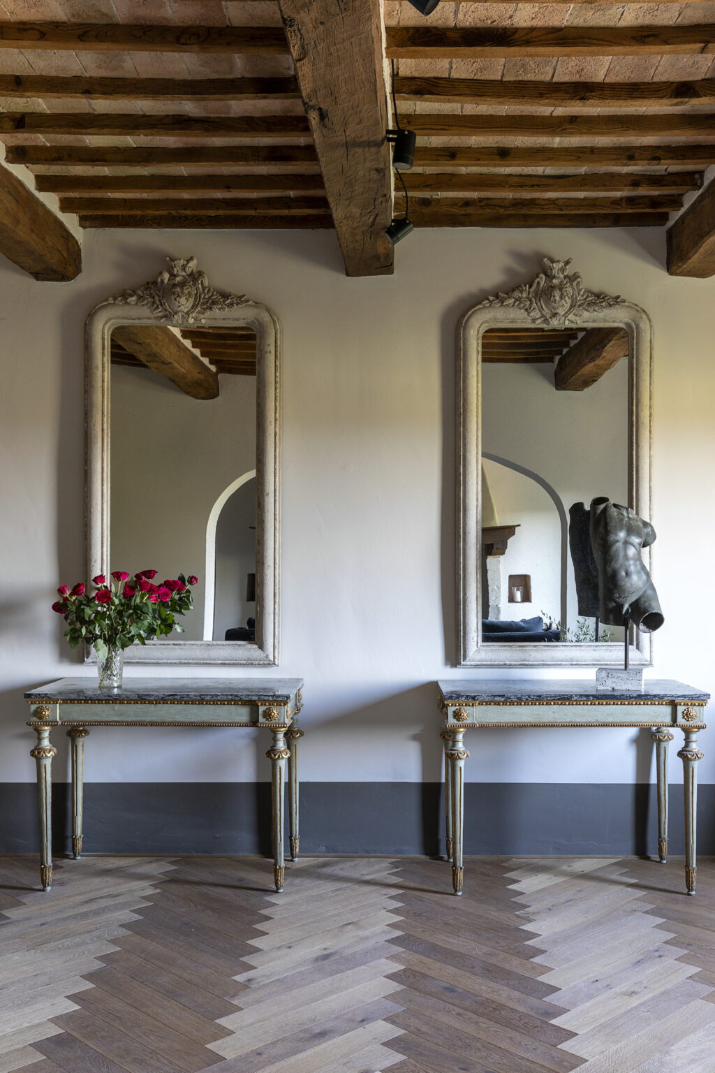 Elegant interior featuring two ornate mirrors above decorative tables, adorned with a vase of red roses, showcasing a sophisticated design aesthetic. | Only on SopranoVillas