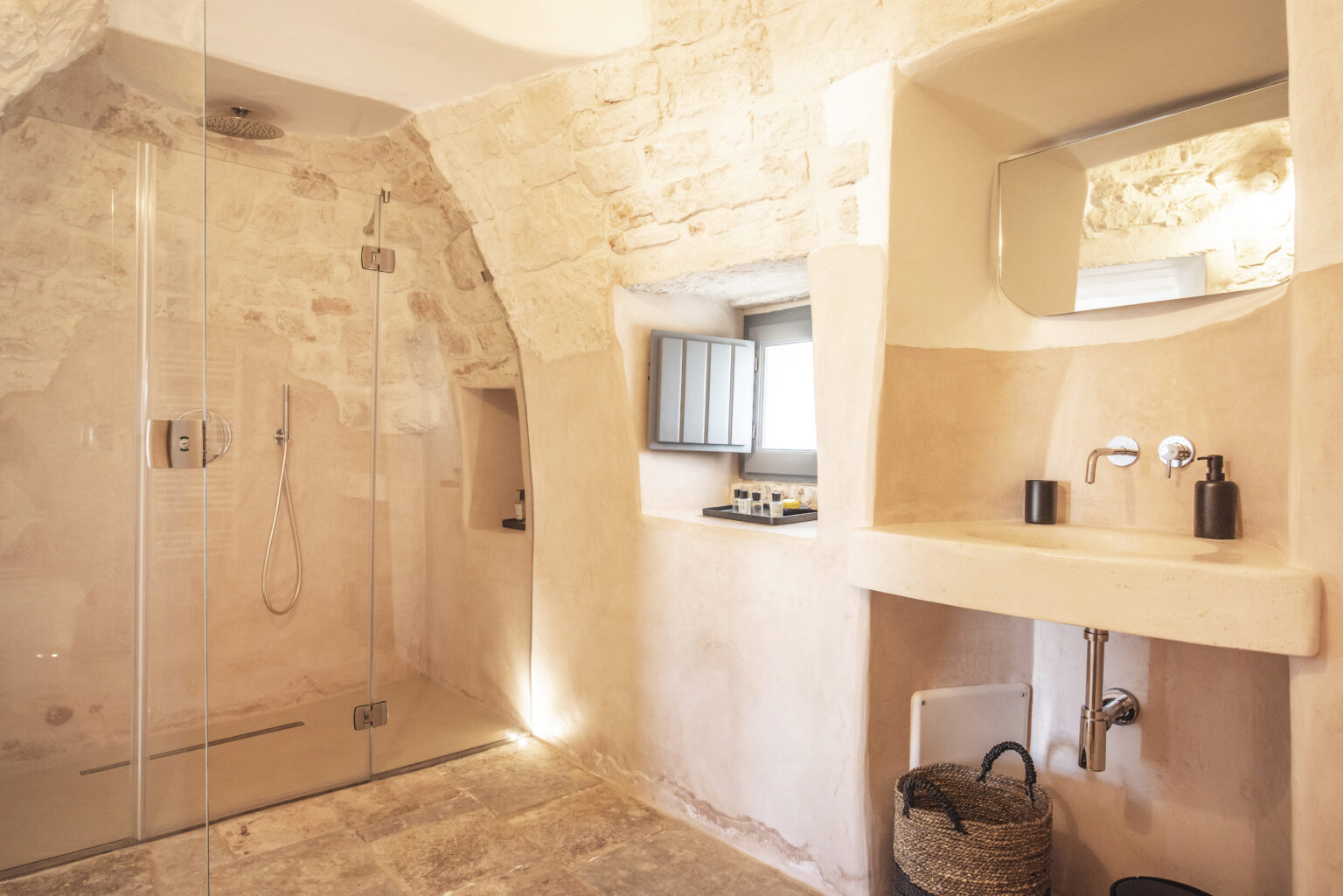 Modern bathroom interior featuring a glass shower, minimalist sink area, and natural stone walls, highlighting a blend of contemporary design and rustic charm. | Only on SopranoVillas