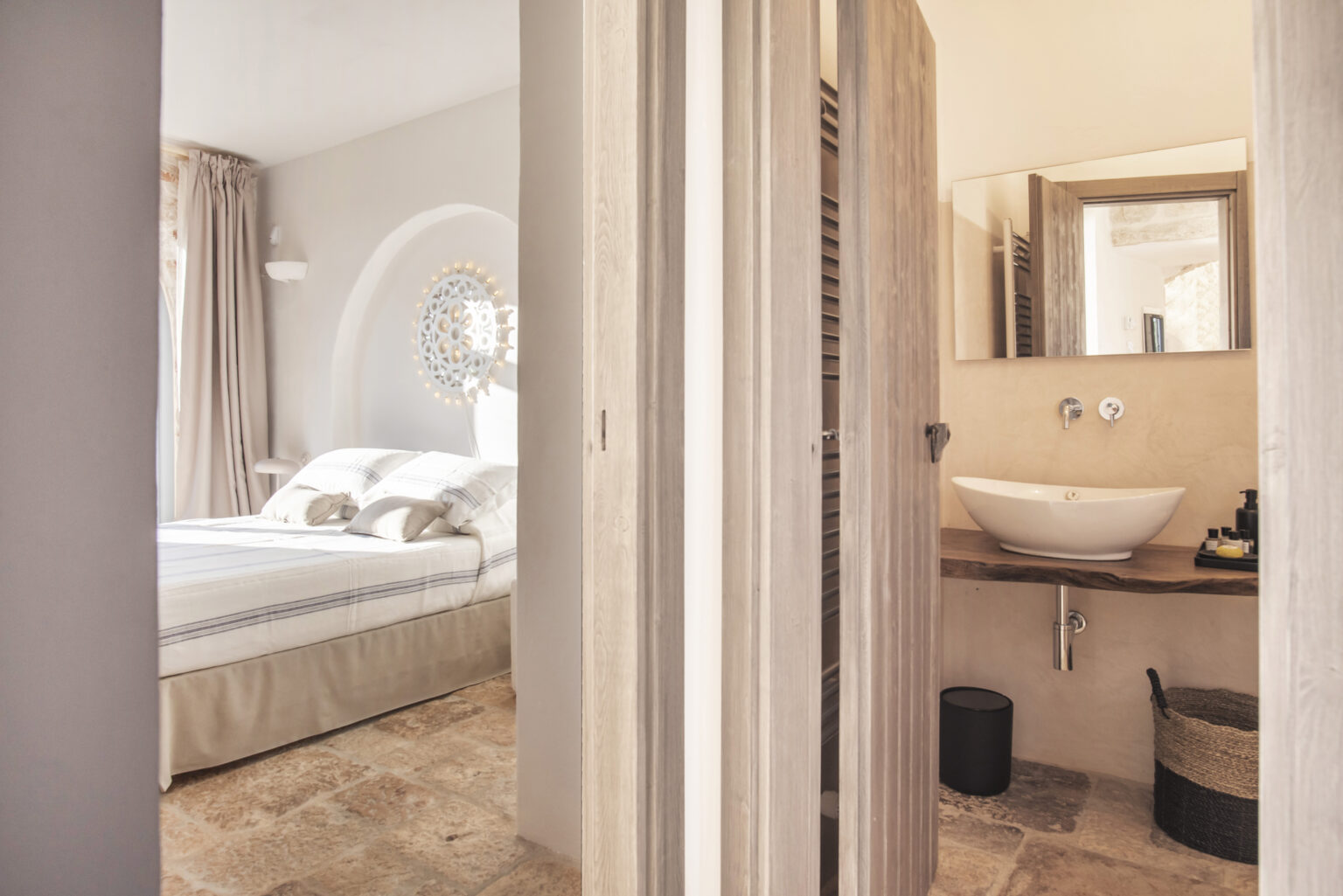 Interior view of a stylish bedroom and bathroom, featuring a cozy bed with soft linens, natural light, and modern decor elements, highlighting a seamless transition between the two spaces. | Only on SopranoVillas