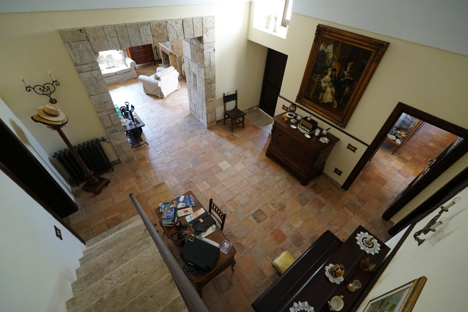 Spacious interior view of a well-decorated home, featuring a tiled floor, elegant staircase, and a cozy living area with natural light. The decor includes artwork and furniture that enhance the welcoming atmosphere. | Only on SopranoVillas