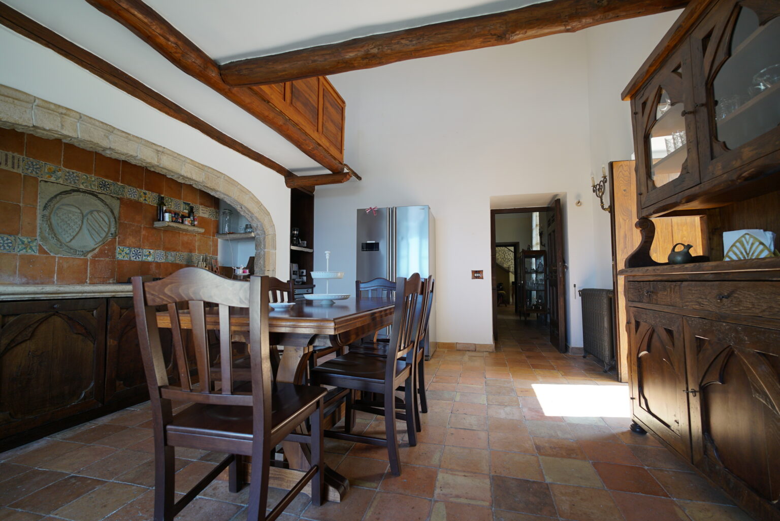 Spacious rustic kitchen with wooden dining table and chairs, featuring exposed beams and tiled flooring, showcasing a warm and inviting atmosphere. | Only on SopranoVillas