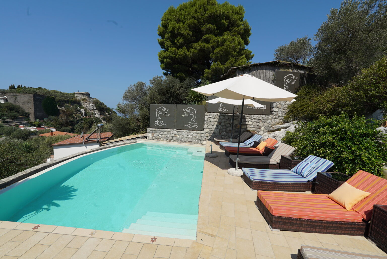Luxury villa with a private swimming pool, surrounded by lush greenery and comfortable lounge chairs, perfect for relaxation under the sun. | Only on SopranoVillas