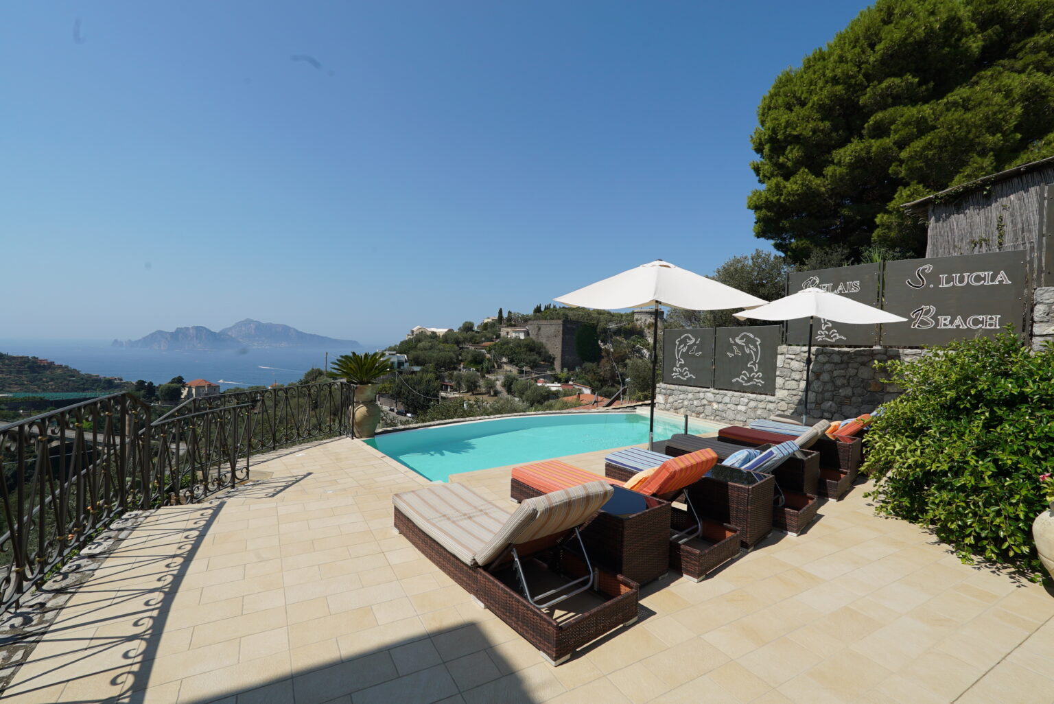 Luxurious villa with a private pool overlooking a scenic landscape, featuring sun loungers and umbrellas for relaxation in a tranquil setting. | Only on SopranoVillas