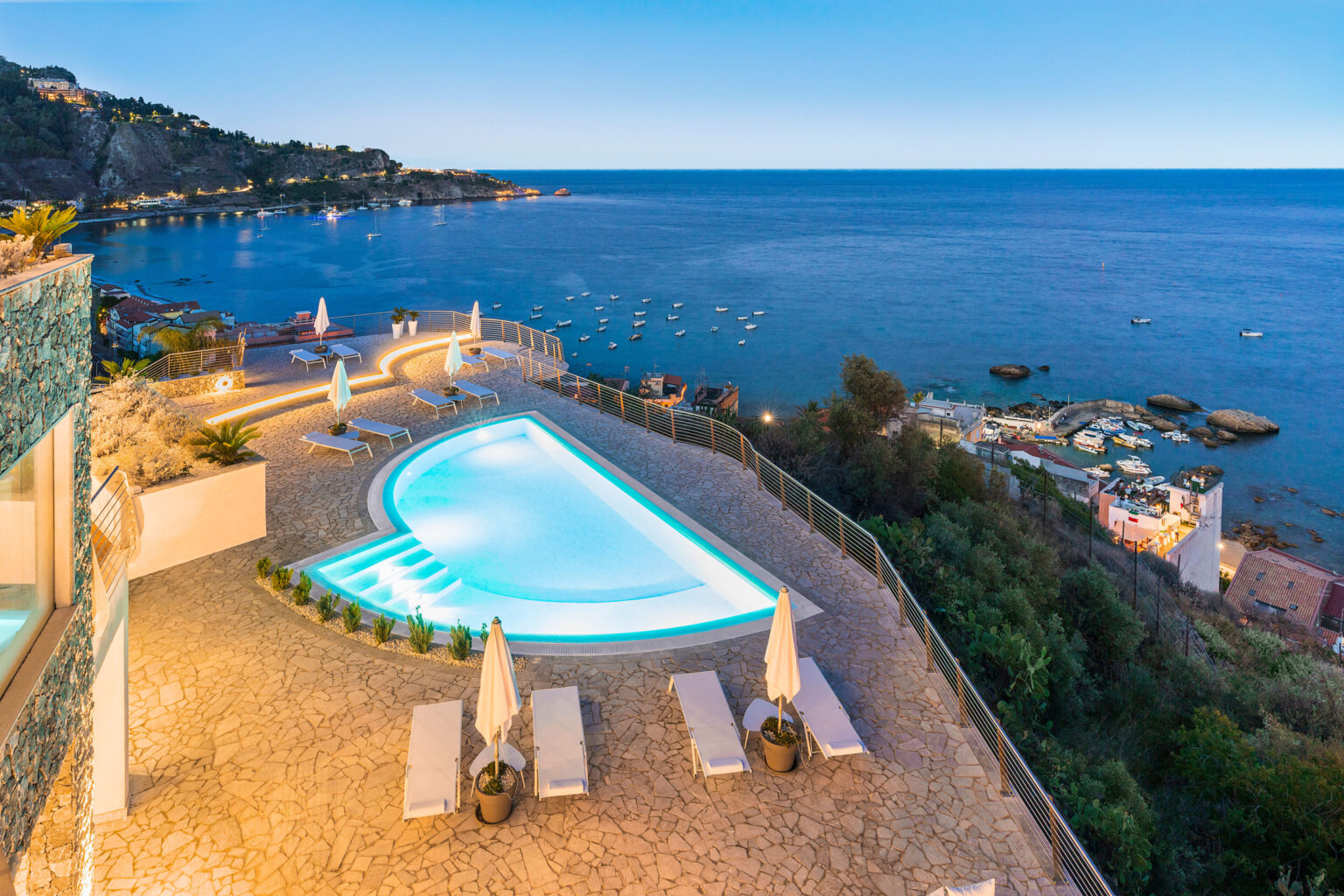 Luxury villa with a stunning infinity pool overlooking the ocean at sunset, featuring sun loungers and scenic coastal views. | Only on SopranoVillas