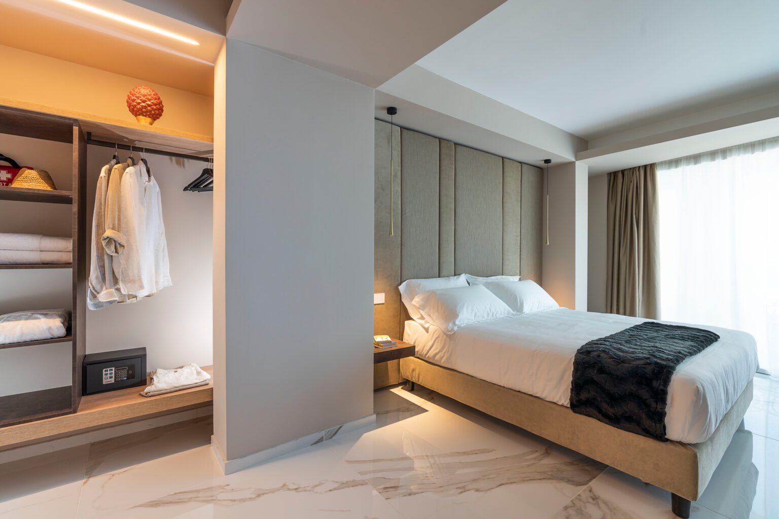 Modern bedroom interior featuring a queen-sized bed, stylish bedding, and a spacious wardrobe with neatly arranged clothes. Natural light floods in through large windows, enhancing the contemporary design and serene atmosphere. | Only on SopranoVillas