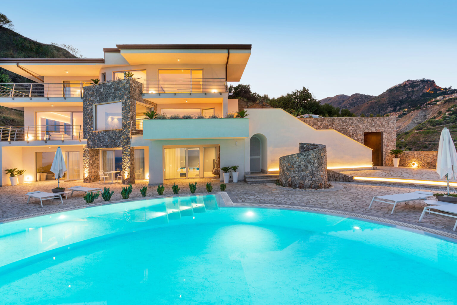 Modern luxury villa with a swimming pool, surrounded by mountains, featuring a spacious outdoor area and contemporary architecture. Ideal for upscale retreats and vacations. | Only on SopranoVillas