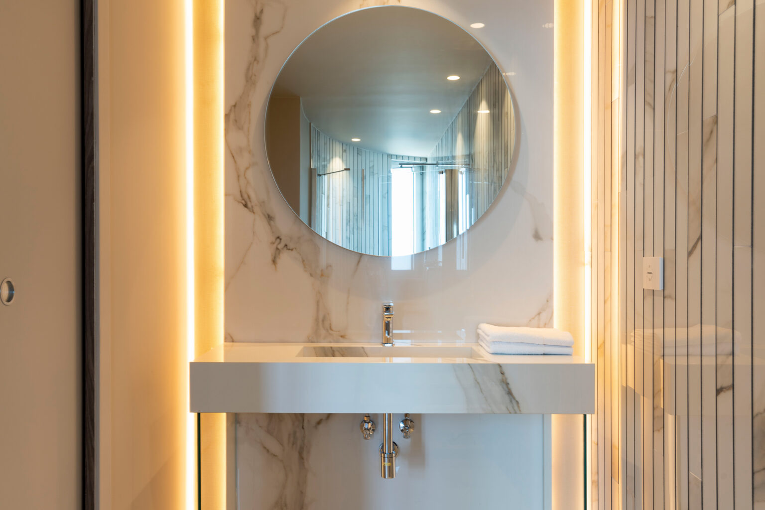 Modern bathroom design featuring a circular mirror, sleek marble sink, and ambient lighting. | Only on SopranoVillas