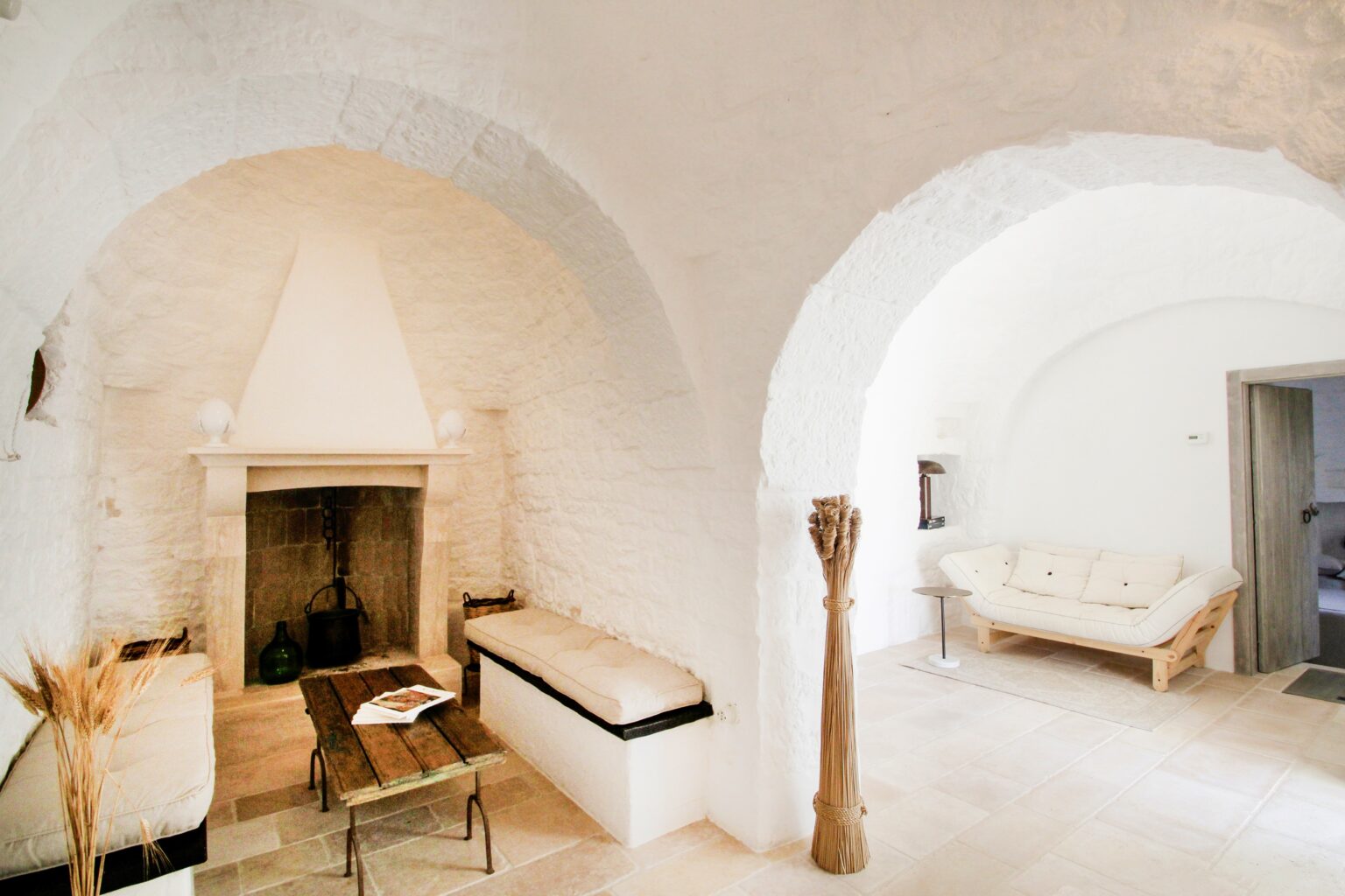 Cozy interior of a modern living space featuring arched ceilings, a stone fireplace, and minimalist furniture. The room is softly lit, showcasing a blend of natural materials and a warm color palette, perfect for relaxation and comfort. | Only on SopranoVillas
