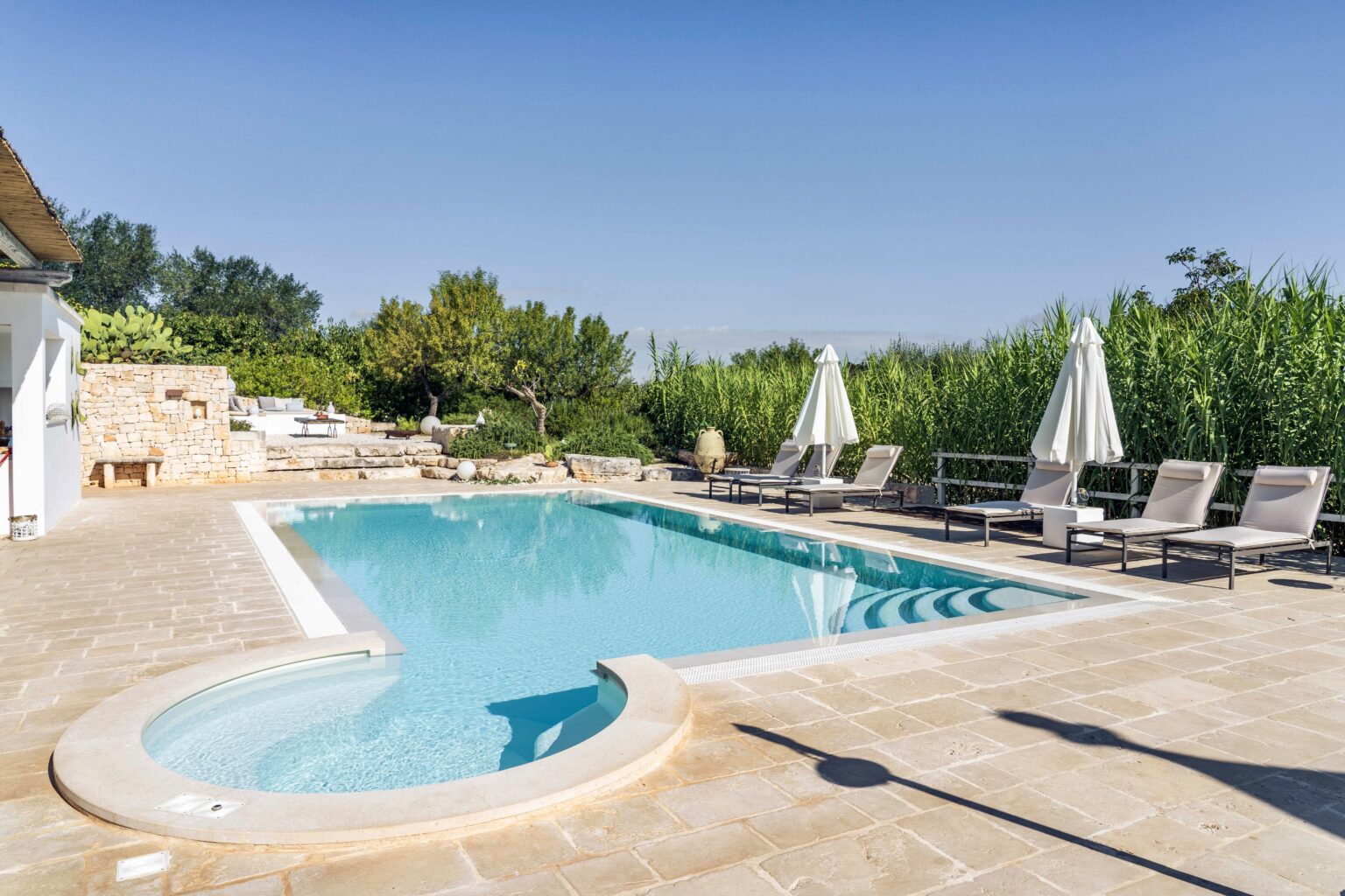 Beautiful outdoor swimming pool surrounded by lounge chairs and lush greenery, perfect for relaxation and leisure in a sunny setting. | Only on SopranoVillas