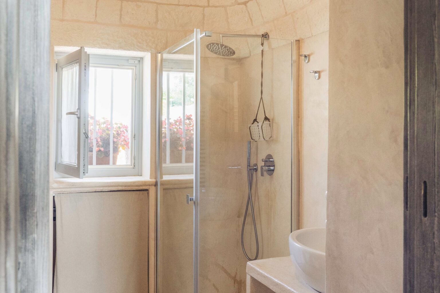 Modern bathroom featuring a glass shower enclosure, natural light from windows, and a minimalist design with beige walls and a sleek bathtub. | Only on SopranoVillas
