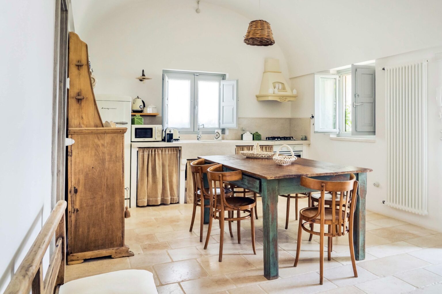 Bright and airy kitchen dining area featuring a wooden table with chairs, natural light from windows, and rustic decor elements. Ideal for family meals and gatherings. | Only on SopranoVillas