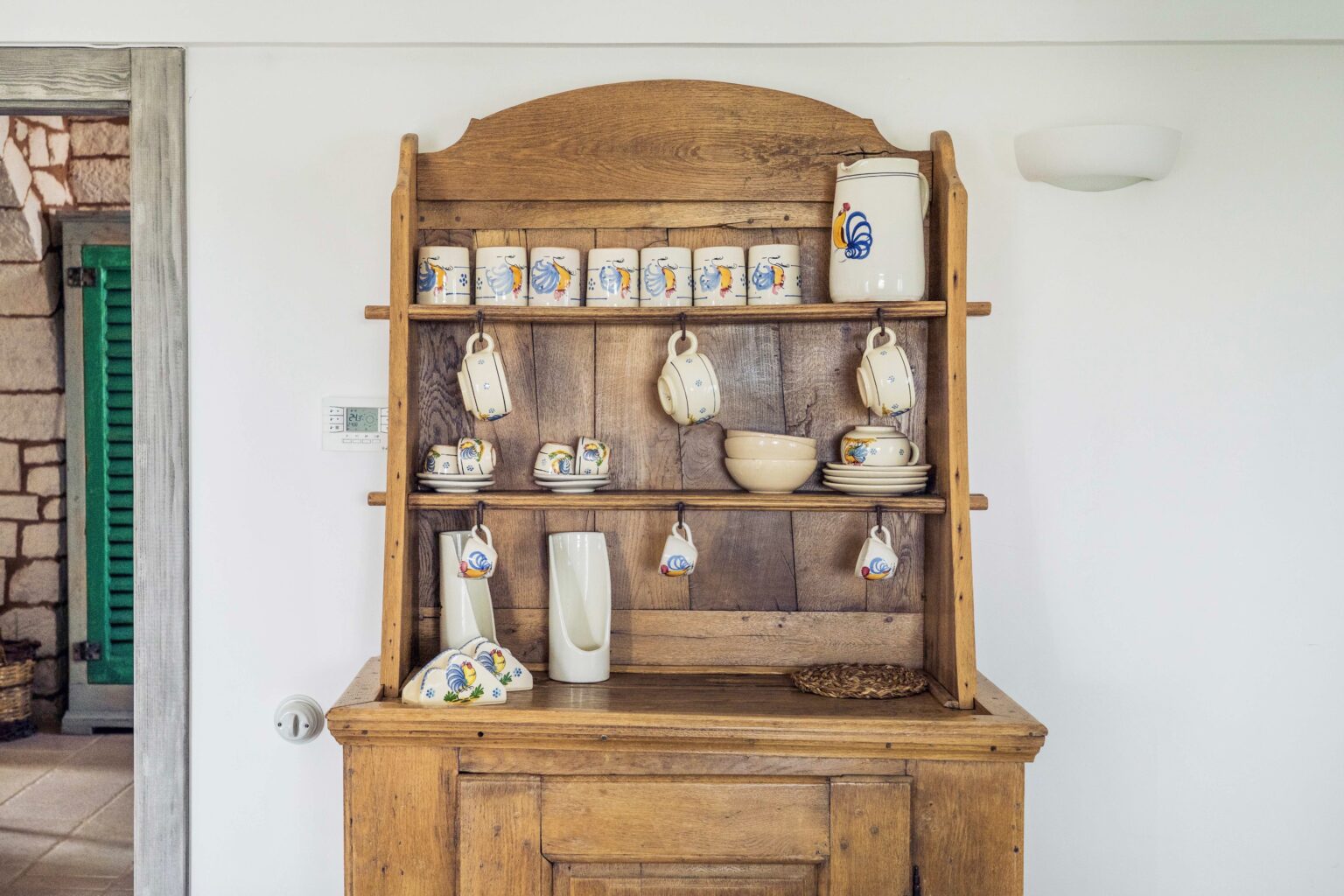 Wooden display cabinet with shelves showcasing vintage ceramics, jars, and decorative items in a bright, modern interior setting. | Only on SopranoVillas