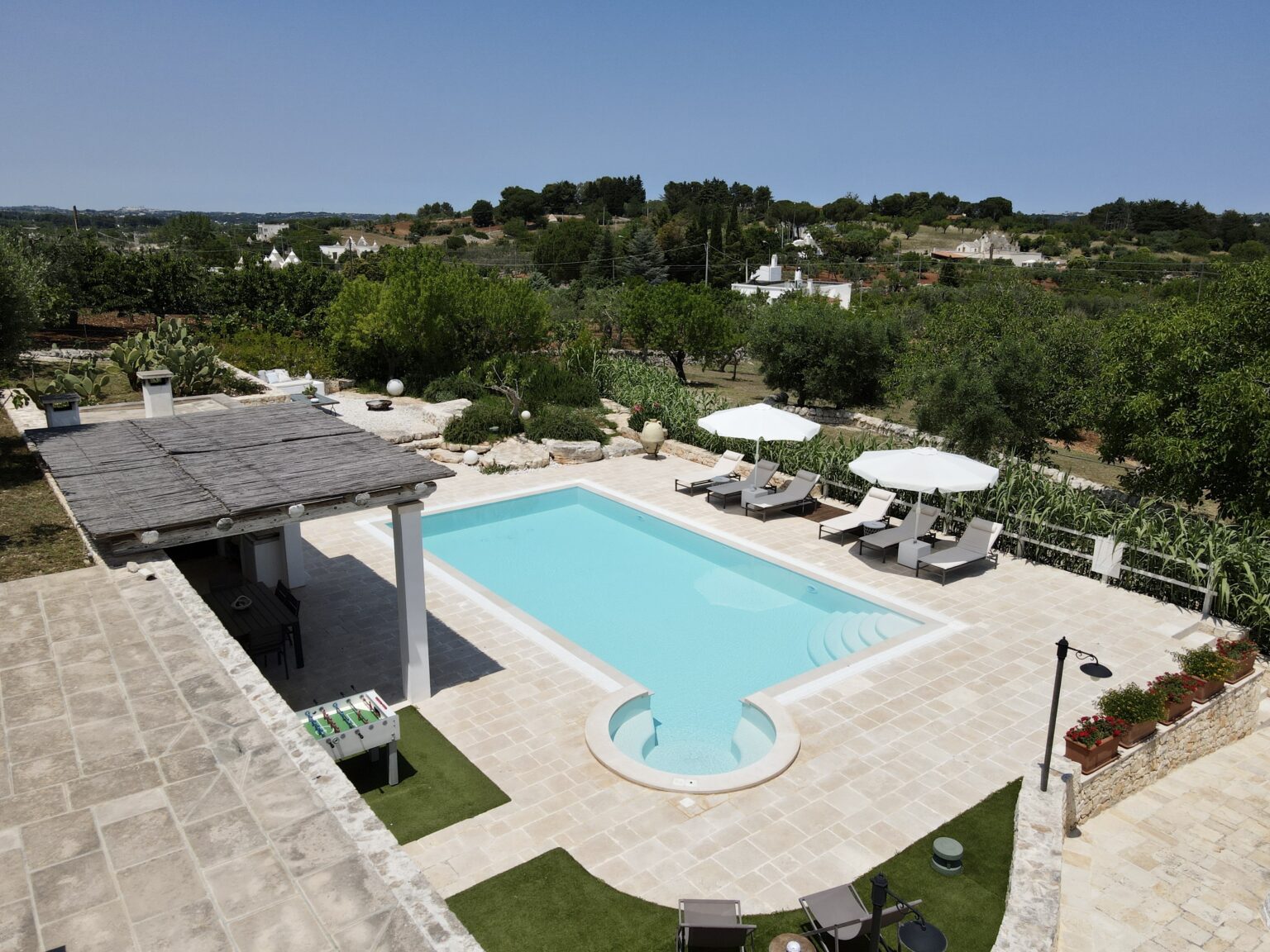 Aerial view of a luxury villa with a large swimming pool, surrounded by lush greenery and lounge chairs, set in a tranquil landscape. Perfect for relaxation and outdoor gatherings. | Only on SopranoVillas