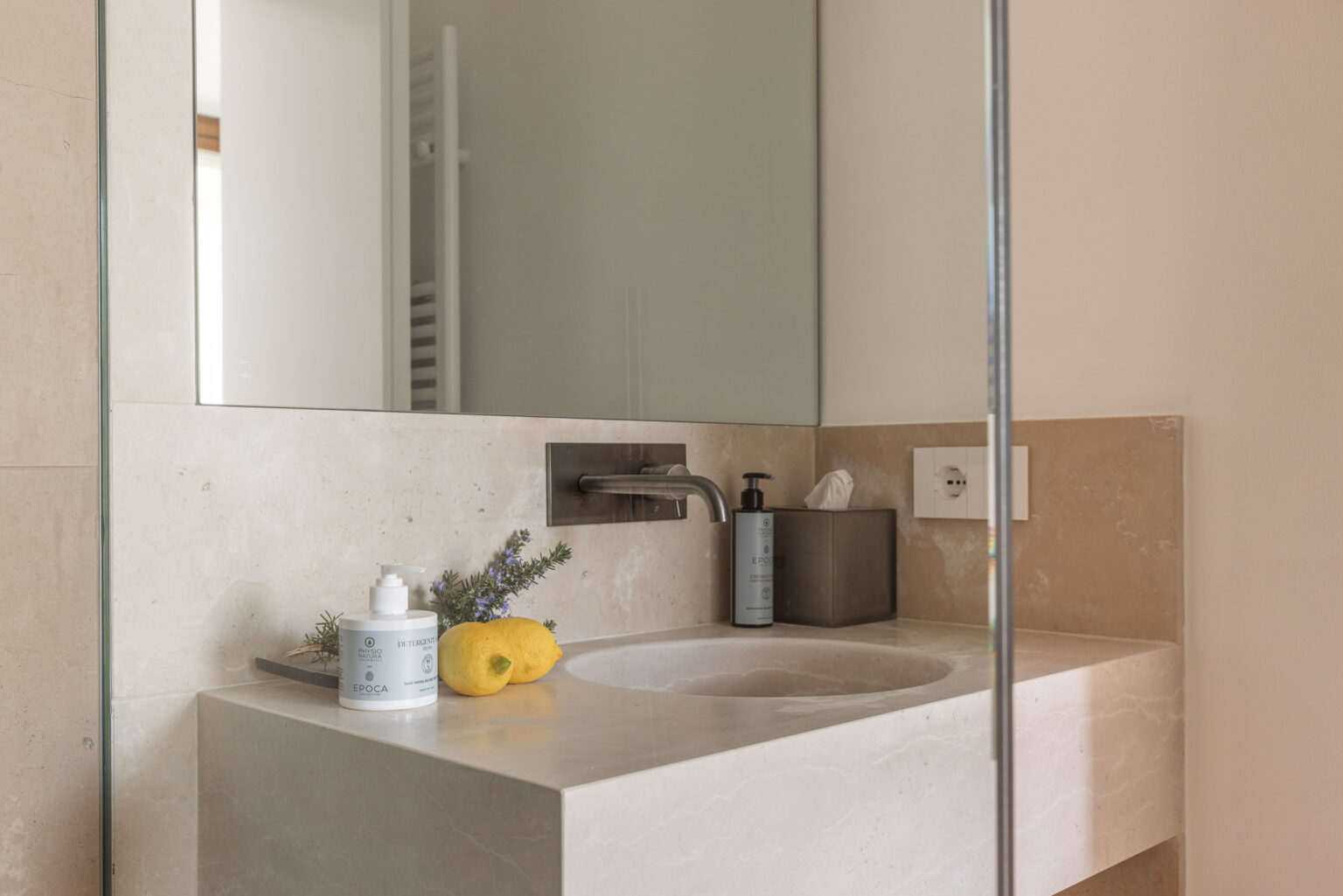 Modern bathroom sink with a sleek design, featuring a mirror, a stylish faucet, and natural elements like lemons and lavender. The countertop displays skincare products, creating an inviting and serene atmosphere. | Only on SopranoVillas