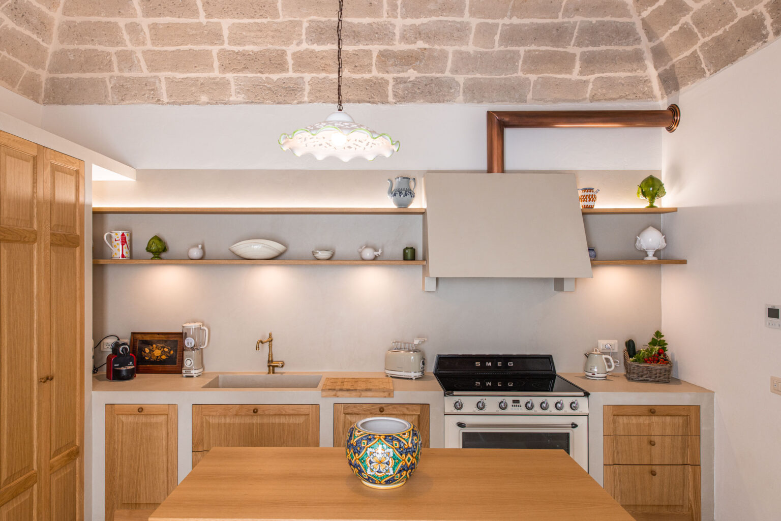 Modern kitchen interior featuring wooden cabinetry, a sleek stove, and minimalist shelving. The design includes warm lighting and decorative elements, creating a stylish and inviting atmosphere. | Only on SopranoVillas