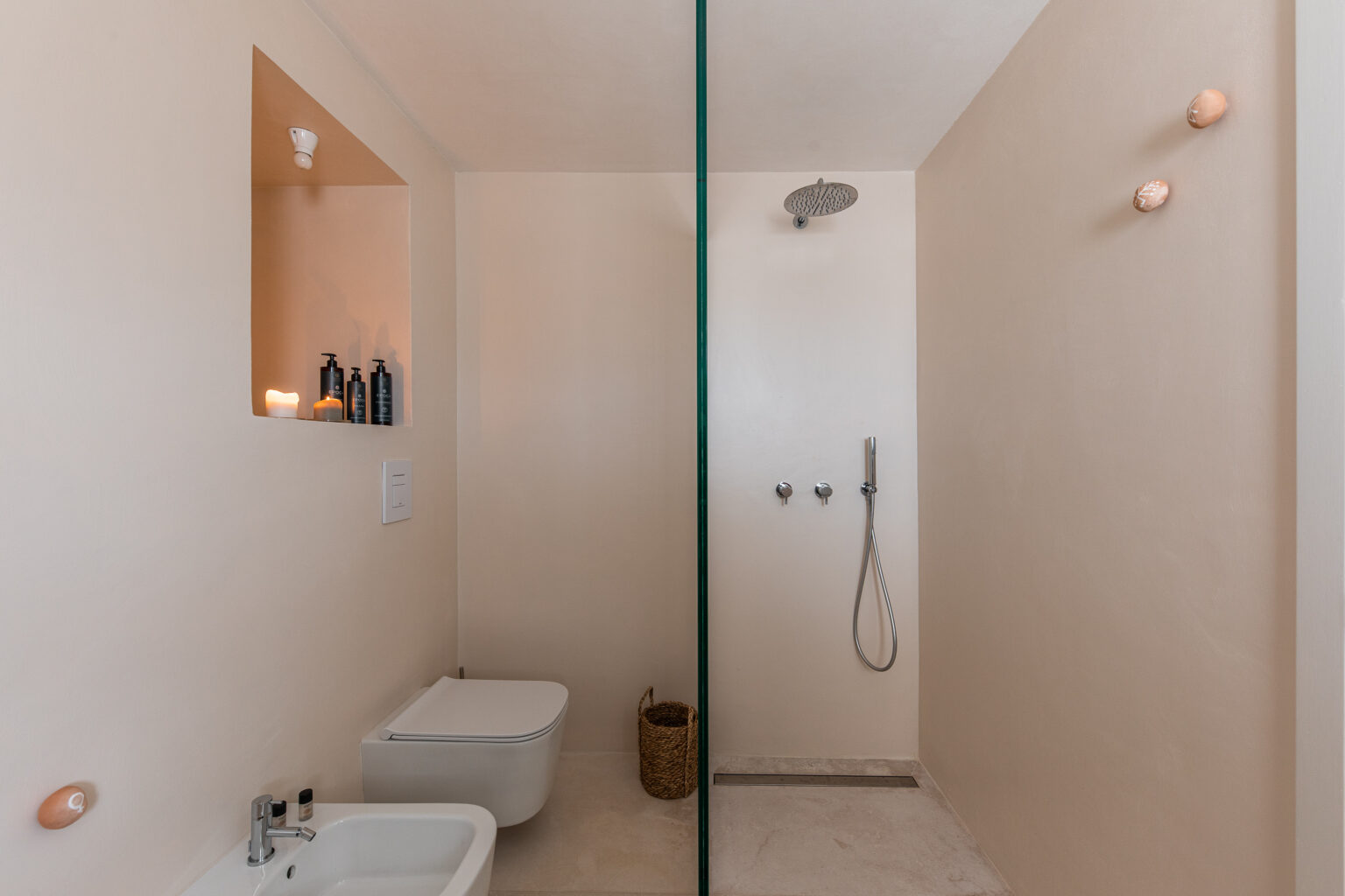 Modern bathroom design featuring a glass shower enclosure, bidet, and minimalist decor. The light-colored walls create a spacious atmosphere, complemented by stylish fixtures and a niche for toiletries. | Only on SopranoVillas