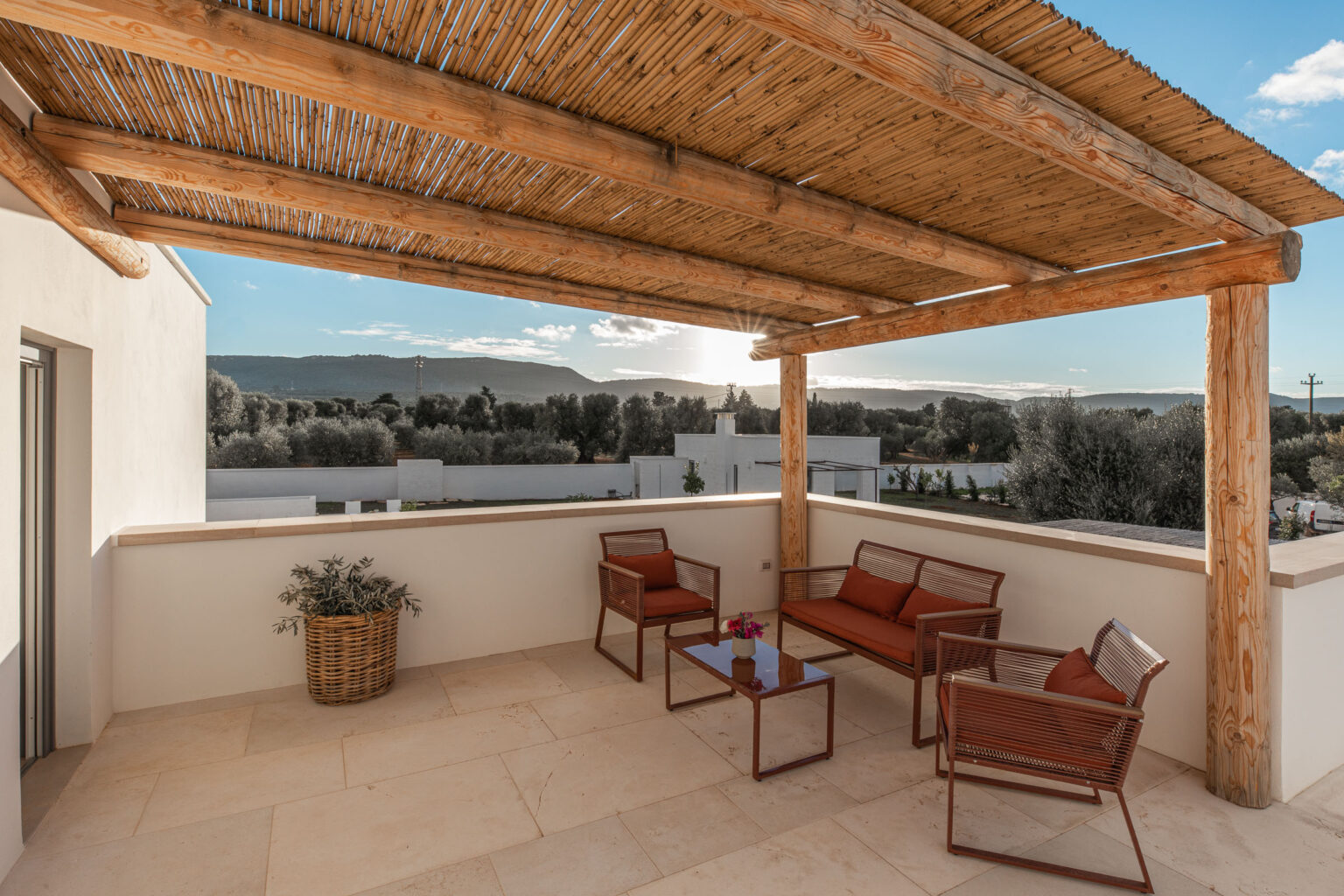 Modern outdoor terrace with wooden pergola, featuring cozy seating and a table, overlooking scenic hills and greenery. Ideal for relaxation and enjoying the view. | Only on SopranoVillas