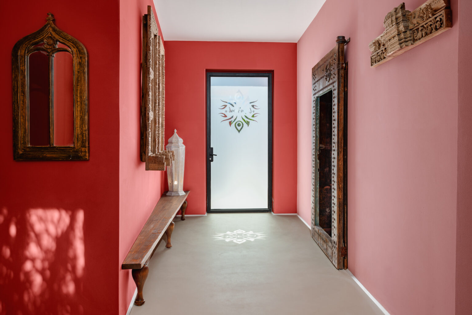 Bright hallway featuring vibrant pink walls, decorative mirrors, and a frosted glass door with floral design, creating a welcoming atmosphere. | Only on SopranoVillas
