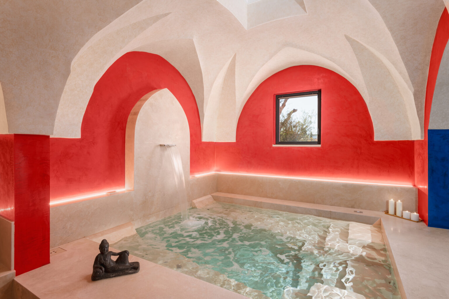 Interior view of a serene spa room featuring a small pool, decorative red and white arches, and ambient lighting, creating a relaxing atmosphere for wellness and rejuvenation. | Only on SopranoVillas
