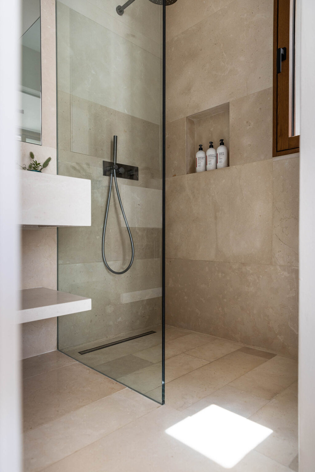 Modern shower design featuring a glass enclosure, stone walls, and minimalist shelving with toiletries. Ideal for contemporary bathroom aesthetics. | Only on SopranoVillas