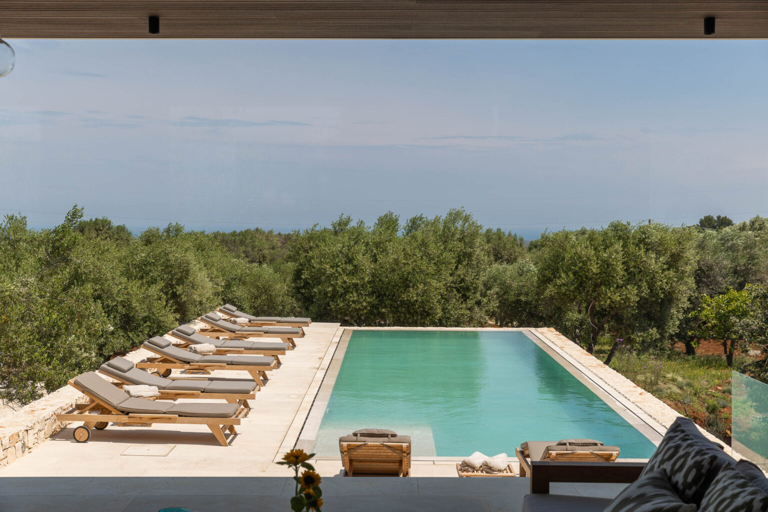 Modern villa with a stunning infinity pool surrounded by olive trees and serene landscape, ideal for luxury relaxation and outdoor living. | Only on SopranoVillas