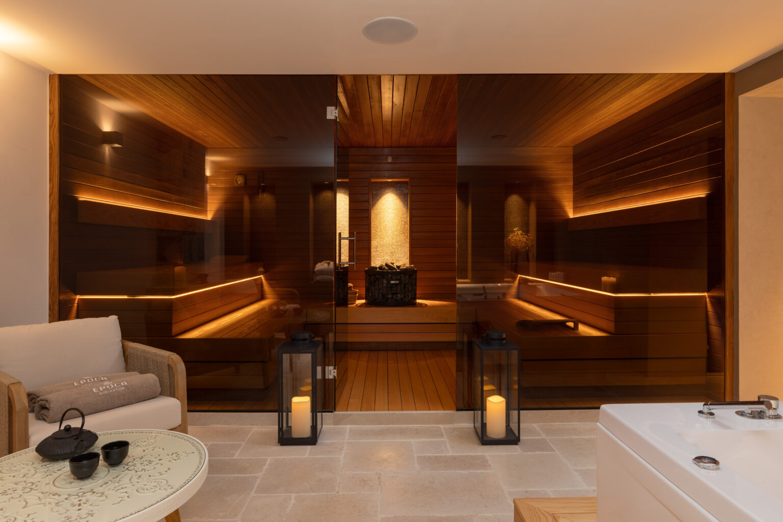 Modern spa interior featuring a wooden sauna with ambient lighting, comfortable seating area, and decorative lanterns. Ideal for relaxation and wellness. | Only on SopranoVillas