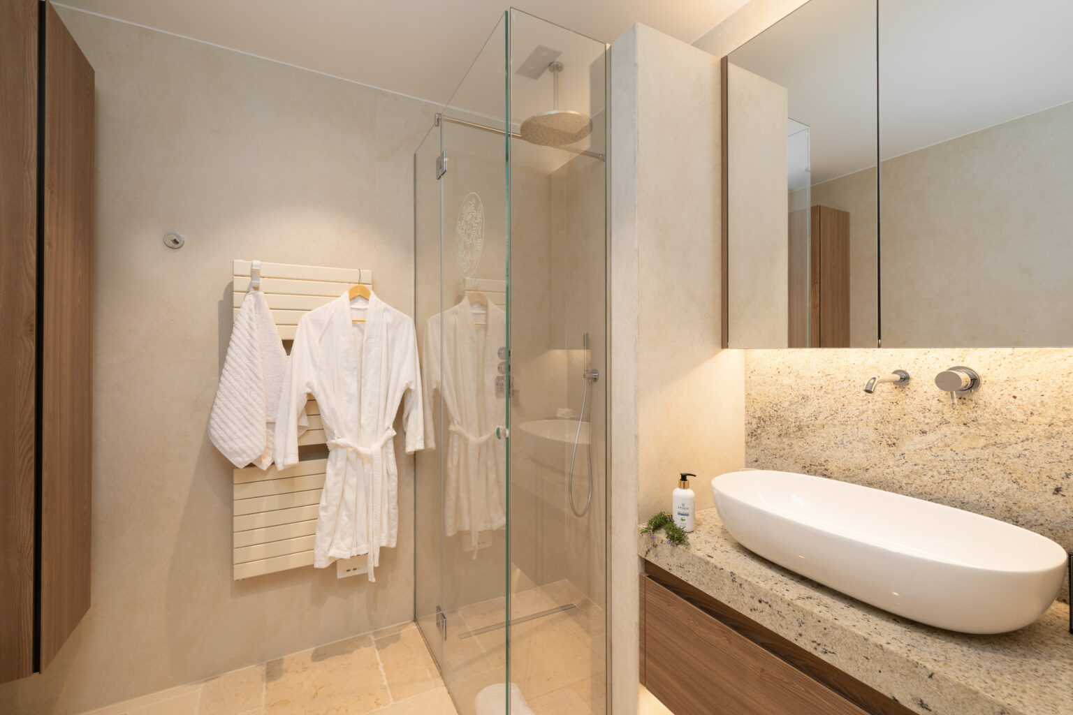 Modern bathroom featuring a glass shower, elegant granite countertop, and neatly hung white bathrobes, showcasing a blend of functionality and style. | Only on SopranoVillas