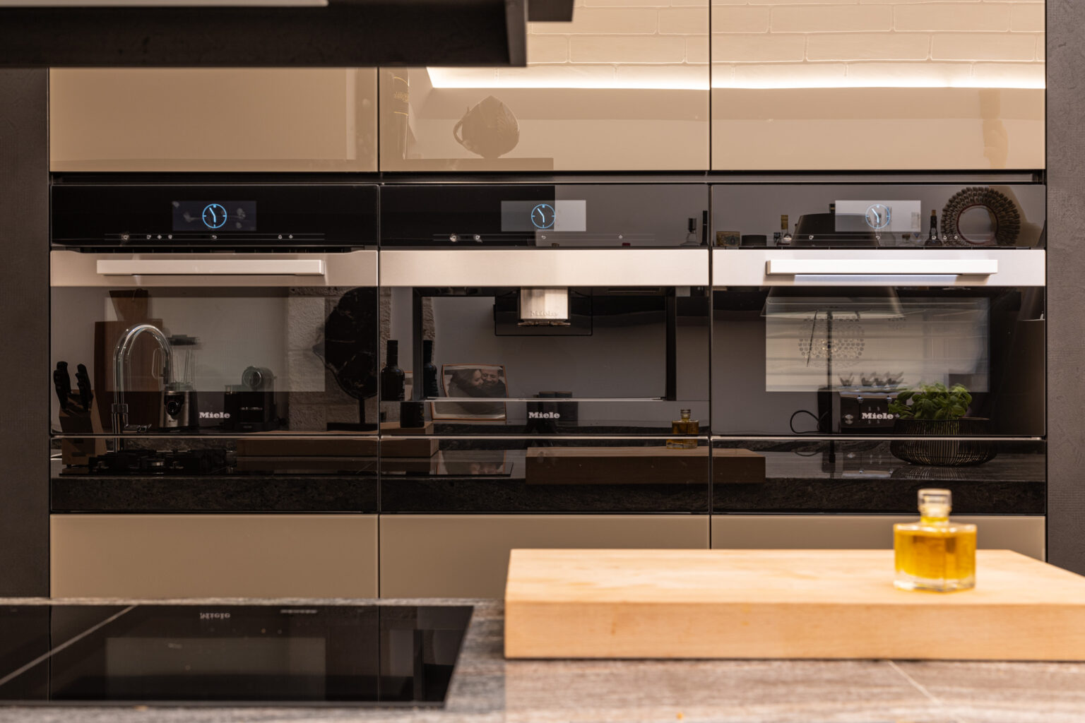 Modern kitchen interior featuring sleek black and beige cabinetry, built-in appliances, and a wooden cutting board with olive oil, showcasing contemporary design and functionality. | Only on SopranoVillas
