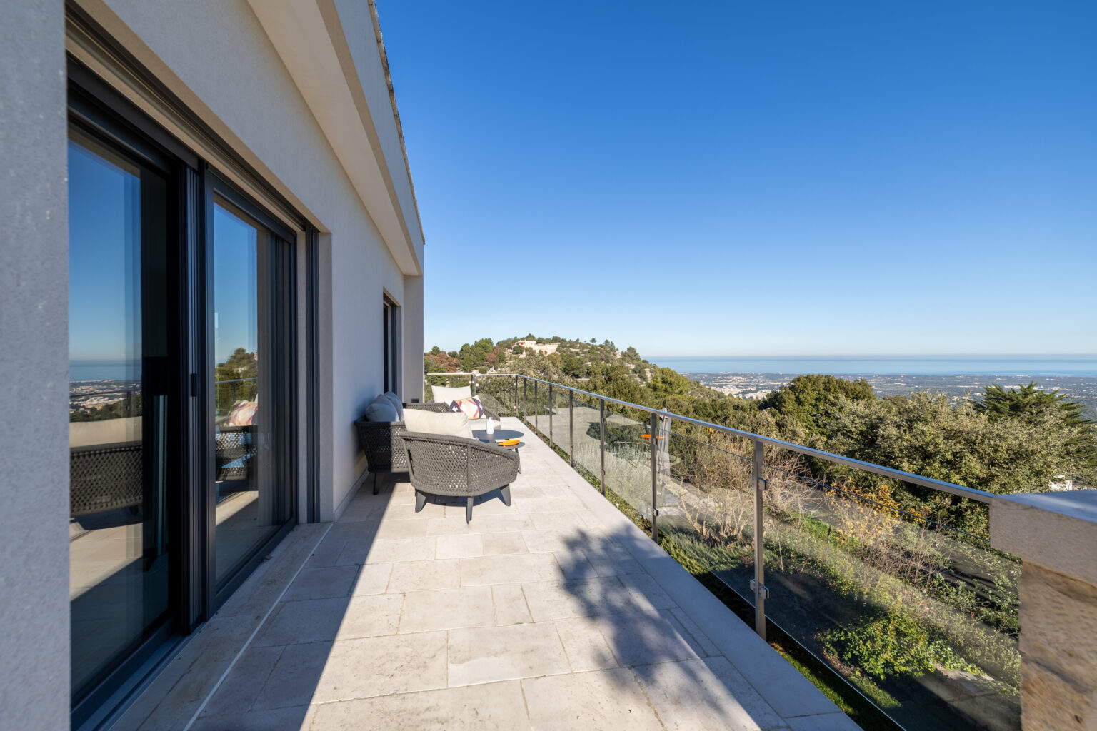 Modern balcony with scenic mountain views, featuring outdoor seating and a clear blue sky. Ideal for relaxation and enjoying nature. | Only on SopranoVillas