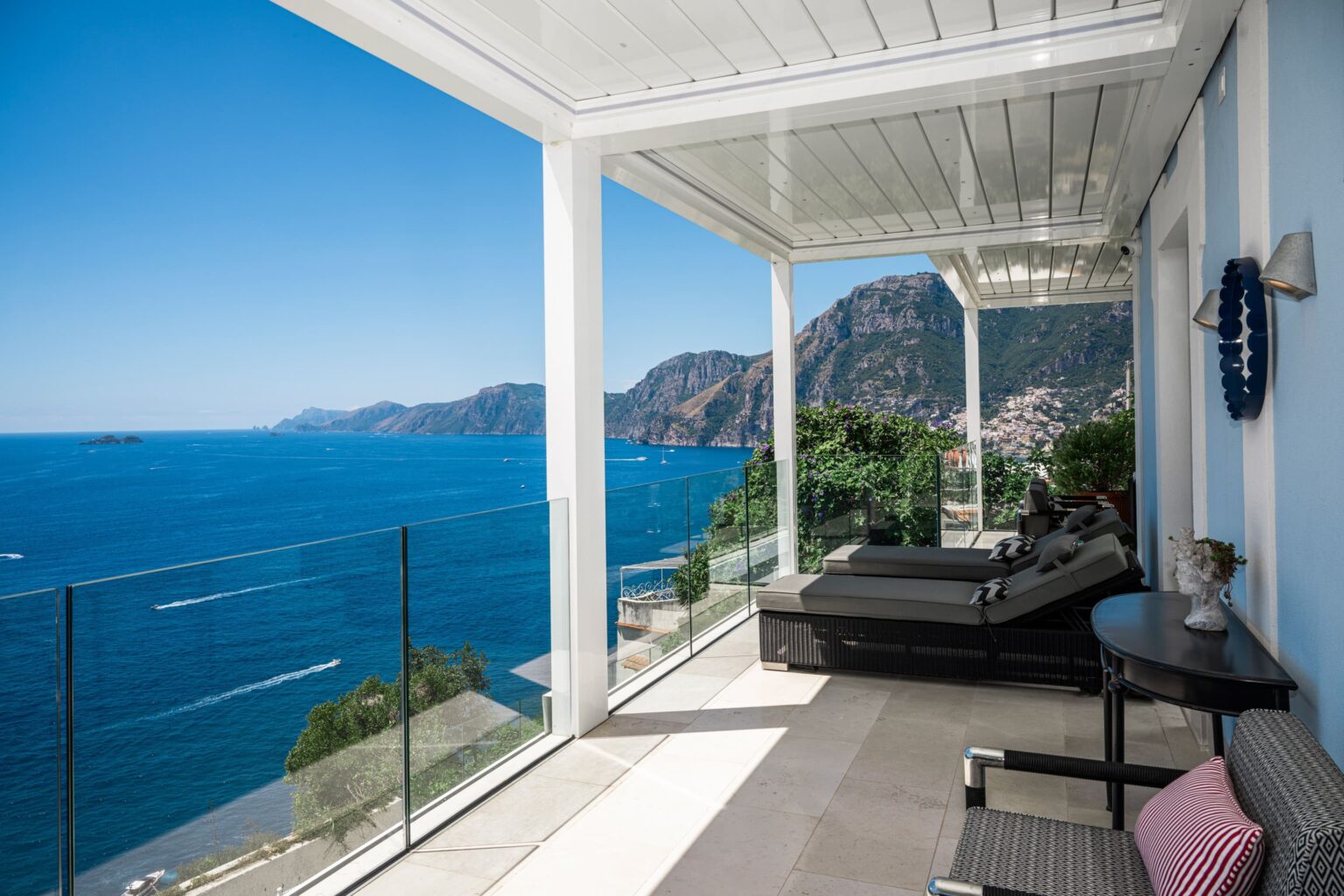 Luxury villa rental in Italy featuring a stunning terrace with panoramic sea views, modern outdoor seating, and a serene coastal landscape. Perfect for a tranquil getaway. | Only on SopranoVillas