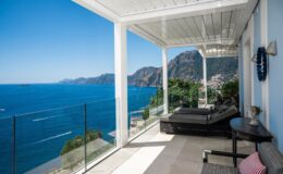 Luxury villa rental in Italy featuring a stunning terrace with panoramic sea views, modern outdoor seating, and a serene coastal landscape. Perfect for a tranquil getaway.