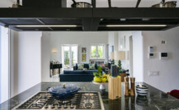 Luxury villa kitchen with modern appliances and elegant decor, showcasing a spacious living area in the background, perfect for vacation rentals in Italy.