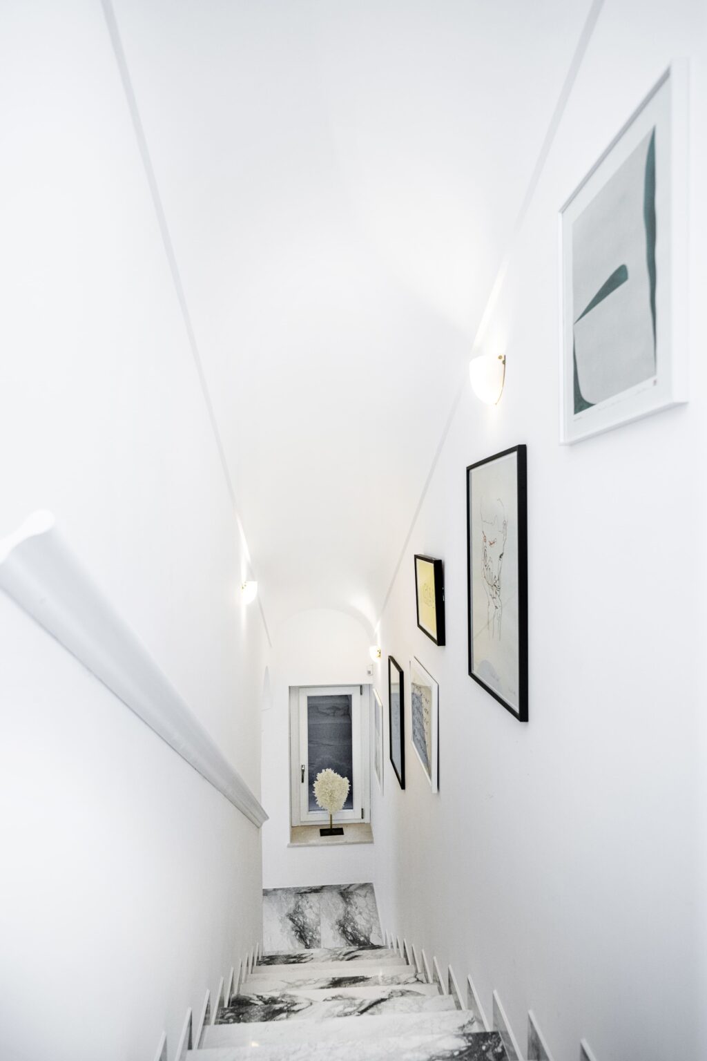 Elegant staircase in a luxury villa for rent in Italy, featuring modern artwork and soft lighting, showcasing the villa's sophisticated interior design. | Only on SopranoVillas