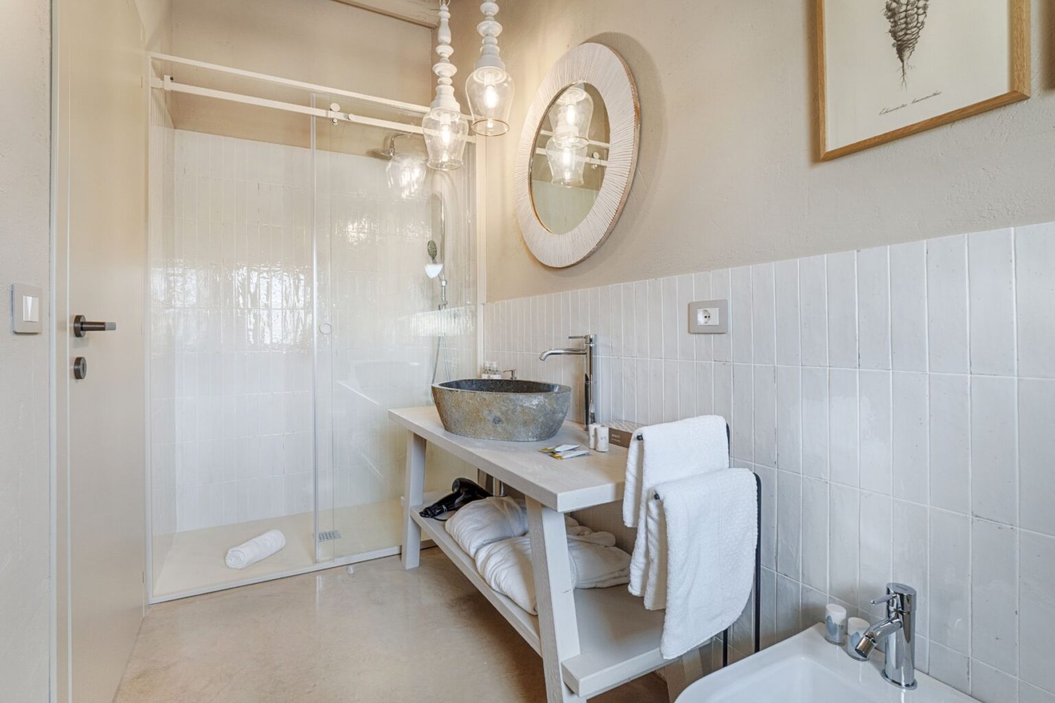 Modern bathroom featuring a glass shower enclosure, a sleek vanity with a stone sink, and elegant lighting fixtures. Fresh towels are neatly arranged, and a stylish mirror complements the minimalist design. | Only on SopranoVillas