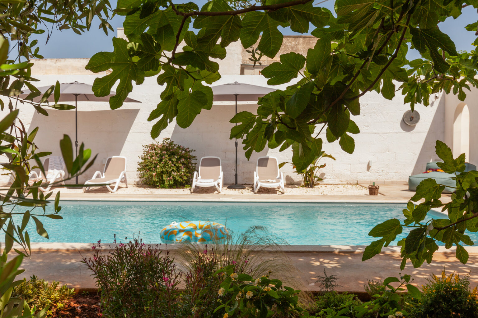 Serene outdoor pool area featuring lounge chairs, umbrellas, and lush greenery, ideal for relaxation and leisure in a tranquil setting. | Only on SopranoVillas