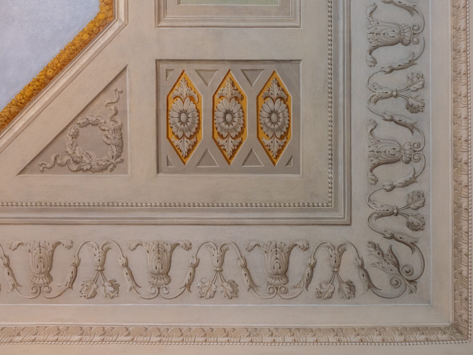 Intricate ceiling design featuring ornate plasterwork, decorative floral motifs, and diamond-shaped panels with gold accents, showcasing classical architectural details. | Only on SopranoVillas