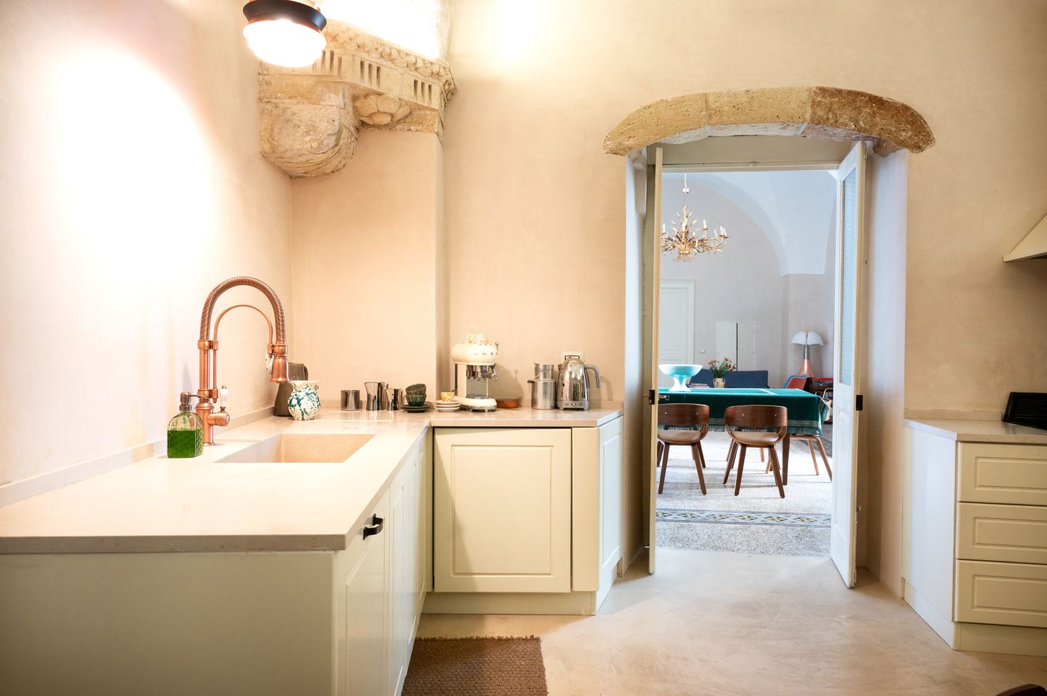 Modern kitchen with a stylish copper faucet, minimalist design, and a view of a cozy living area featuring elegant furniture and decorative lighting. | Only on SopranoVillas