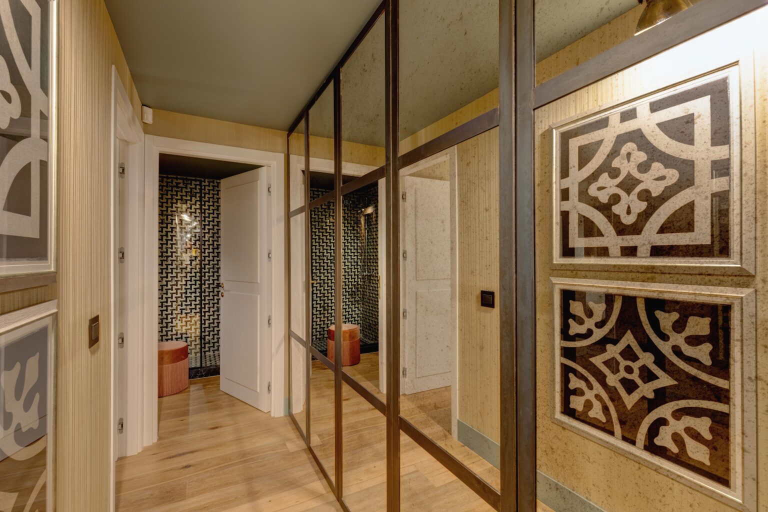 Modern interior hallway featuring decorative mirrors, patterned wallpaper, and wooden flooring. The design includes stylish doors and a contemporary aesthetic with a mix of textures and colors. | Only on SopranoVillas