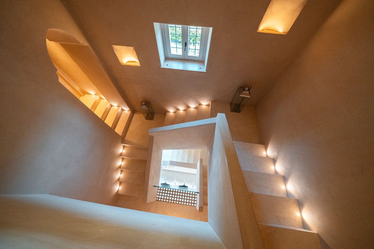 Modern staircase design featuring soft lighting, minimalist decor, and a view of a window above, creating an inviting and spacious atmosphere. | Only on SopranoVillas