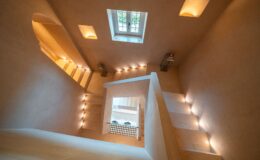Modern staircase design featuring soft lighting, minimalist decor, and a view of a window above, creating an inviting and spacious atmosphere.