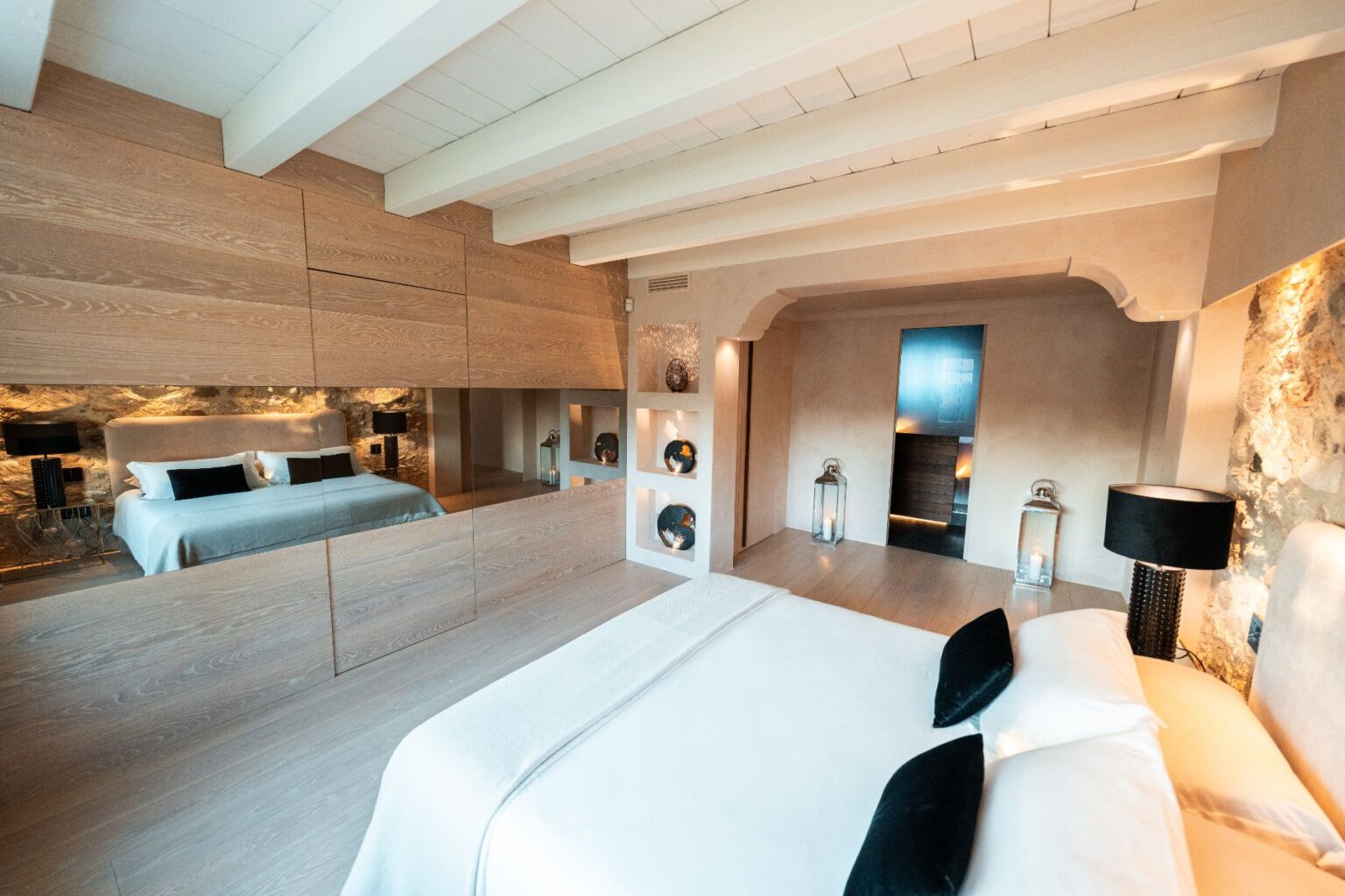 Modern bedroom interior featuring a spacious layout with a large bed, stylish decor, and wooden beams. The room includes mirrored walls, soft lighting, and elegant furnishings, creating a serene and inviting atmosphere. Perfect for a contemporary home design or hotel showcase. | Only on SopranoVillas