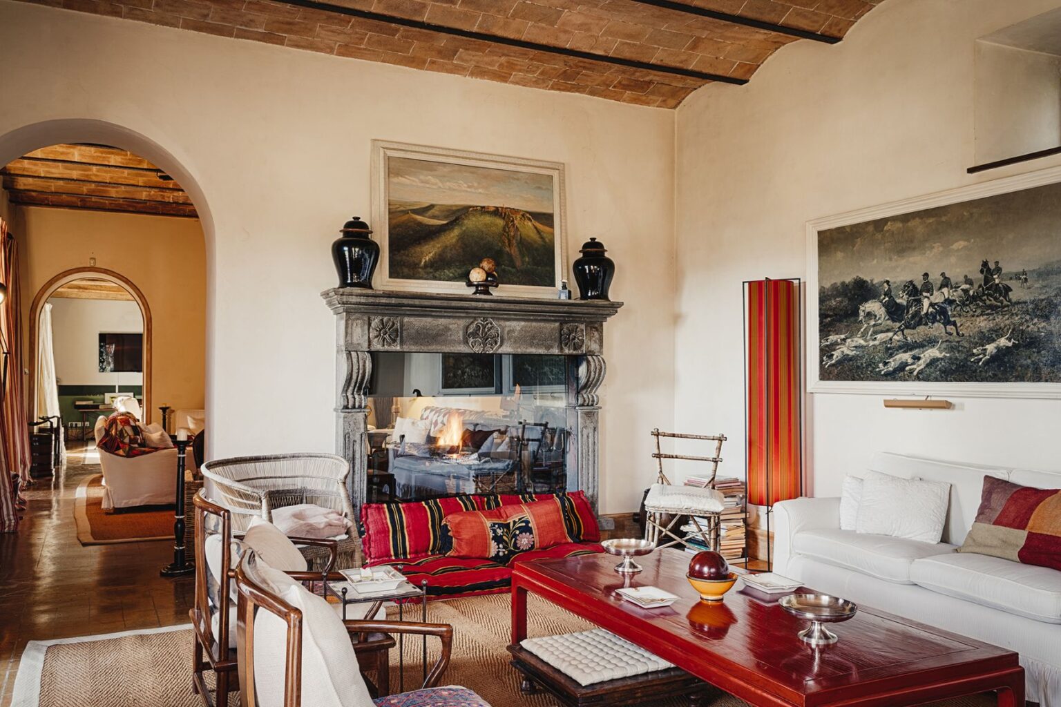 Cozy living room featuring a stone fireplace, comfortable seating, and artistic decor. The space includes a mix of traditional and modern furnishings, warm colors, and natural light, creating an inviting atmosphere perfect for relaxation. | Only on SopranoVillas
