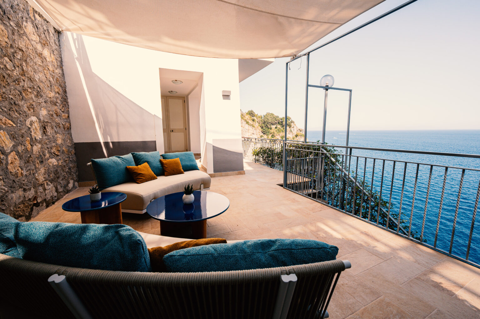 Luxury villa terrace overlooking the sea in Italy, featuring stylish outdoor seating and elegant decor, perfect for relaxing and enjoying breathtaking coastal views. | Only on SopranoVillas