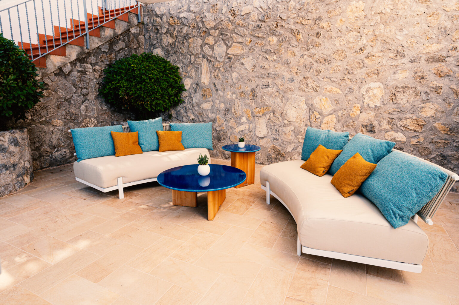 Stylish outdoor seating area with plush cushions and a modern coffee table, surrounded by stone walls, perfect for relaxing in luxury villas for rent in Italy. | Only on SopranoVillas